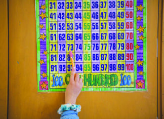 A student uses a math chart to solve an addition problem. Photo by Pablo Unzueta/CalMatters