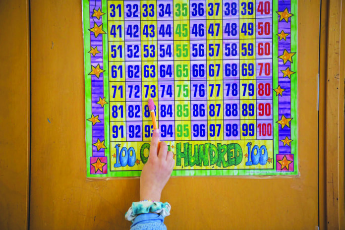 A student uses a math chart to solve an addition problem. Photo by Pablo Unzueta/CalMatters