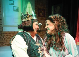 Two actors in medieval-style costumes performing on stage.