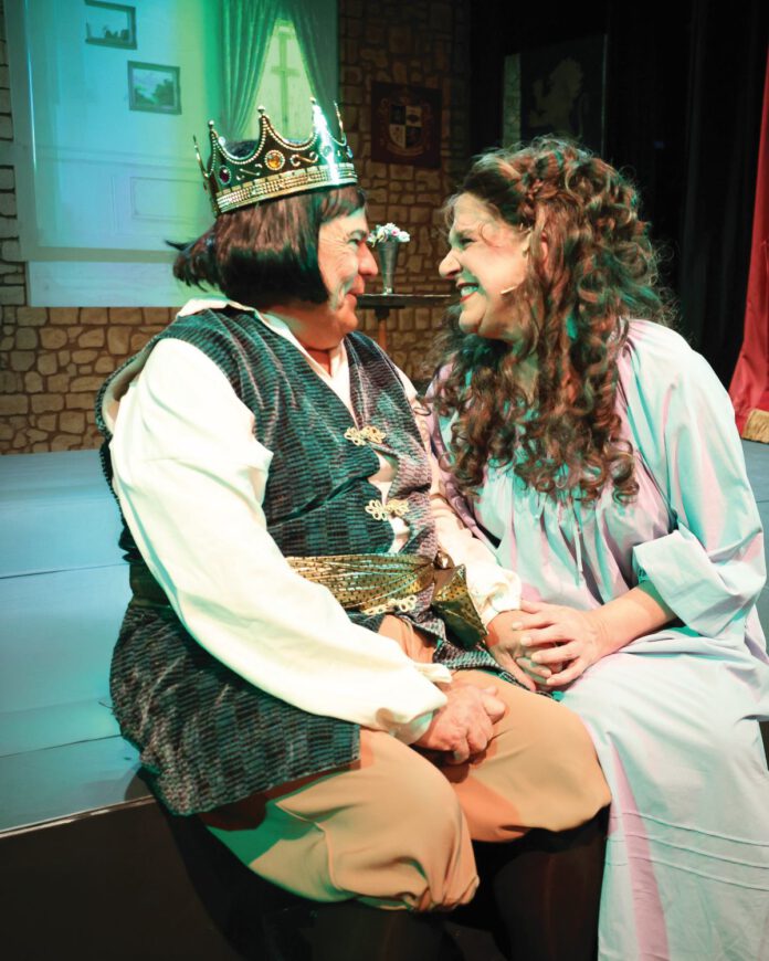 Two actors in medieval-style costumes performing on stage.