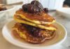 A stack of pancakes topped with roasted grapes and served on a plate.