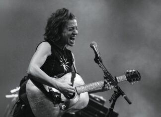Musician Ani DiFranco performing onstage with a guitar.