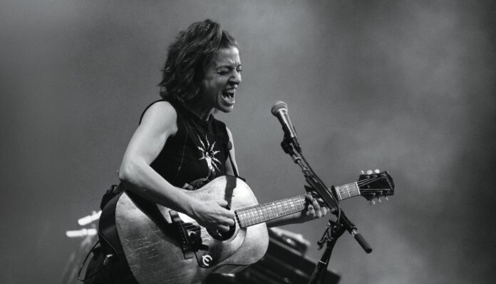 Musician Ani DiFranco performing onstage with a guitar.