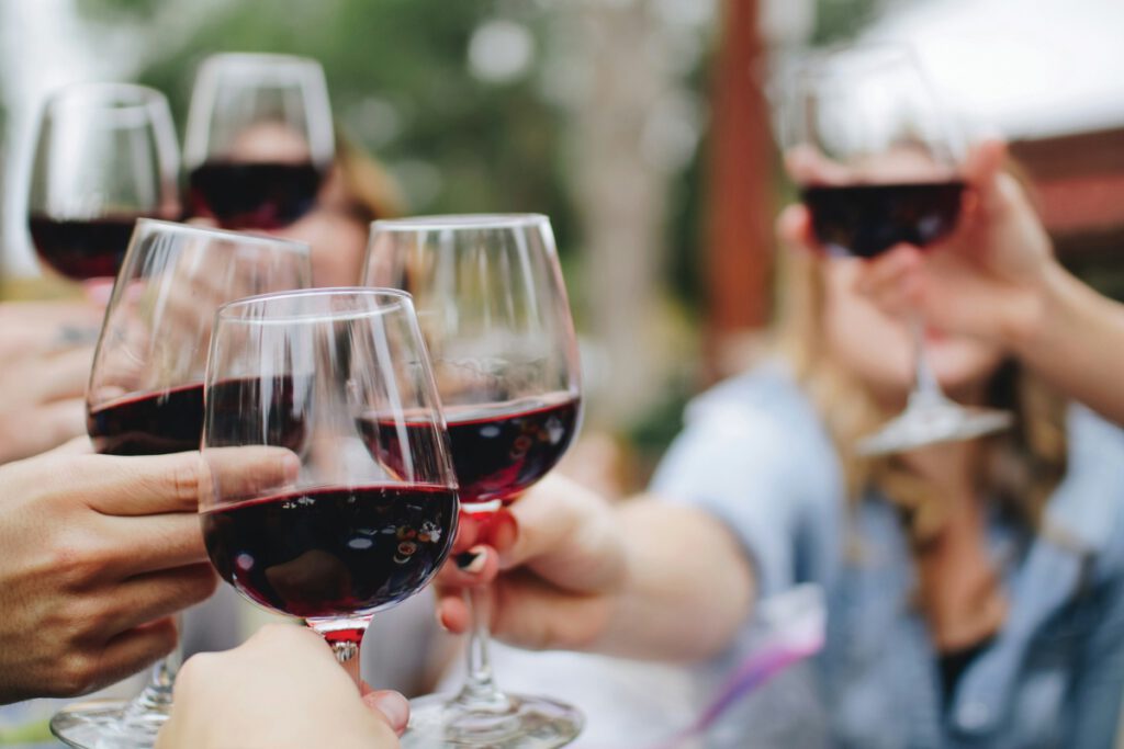 Hands holding stemmed glasses of red wine in a toast