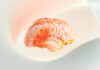 A glowing, translucent digital rendering of a human brain with fiery orange highlights, set against a rippled white background.