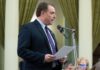 Assemblymember Damon Connolly speaks into a microphone while holding papers at a podium in the California State Capitol.