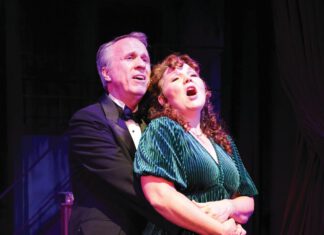 Still Here, Sondheim’s ‘Follies’ in Sonoma A man in a tuxedo stands behind a woman in a green dress, wrapping his arms around her waist as they both sing.