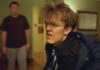 Film Fests in Healdsburg and Cotati Play Long Game with Shorts A young man in a blue jacket and tie looks uncomfortable, with another man in a brown shirt standing behind him in a living room.