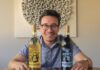 Drink Wine, Save Cats: Chateau Gato Combines Causes in a Single Sip A smiling man in glasses holds two wine bottles labeled "Meowsling" and "Pinotmeow," each featuring a cartoon cat.