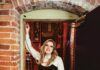 Sound Decisions: Announcing Our 2026 North Bay Music Awards Winners A smiling woman with long blonde hair, a white shirt and black leather pants leans against a brick wall.