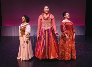Dark Lady: ‘Emilia’ at SRJC Three women in Elizabethan-style gowns stand in a row on a dark stage in front of a magenta background.